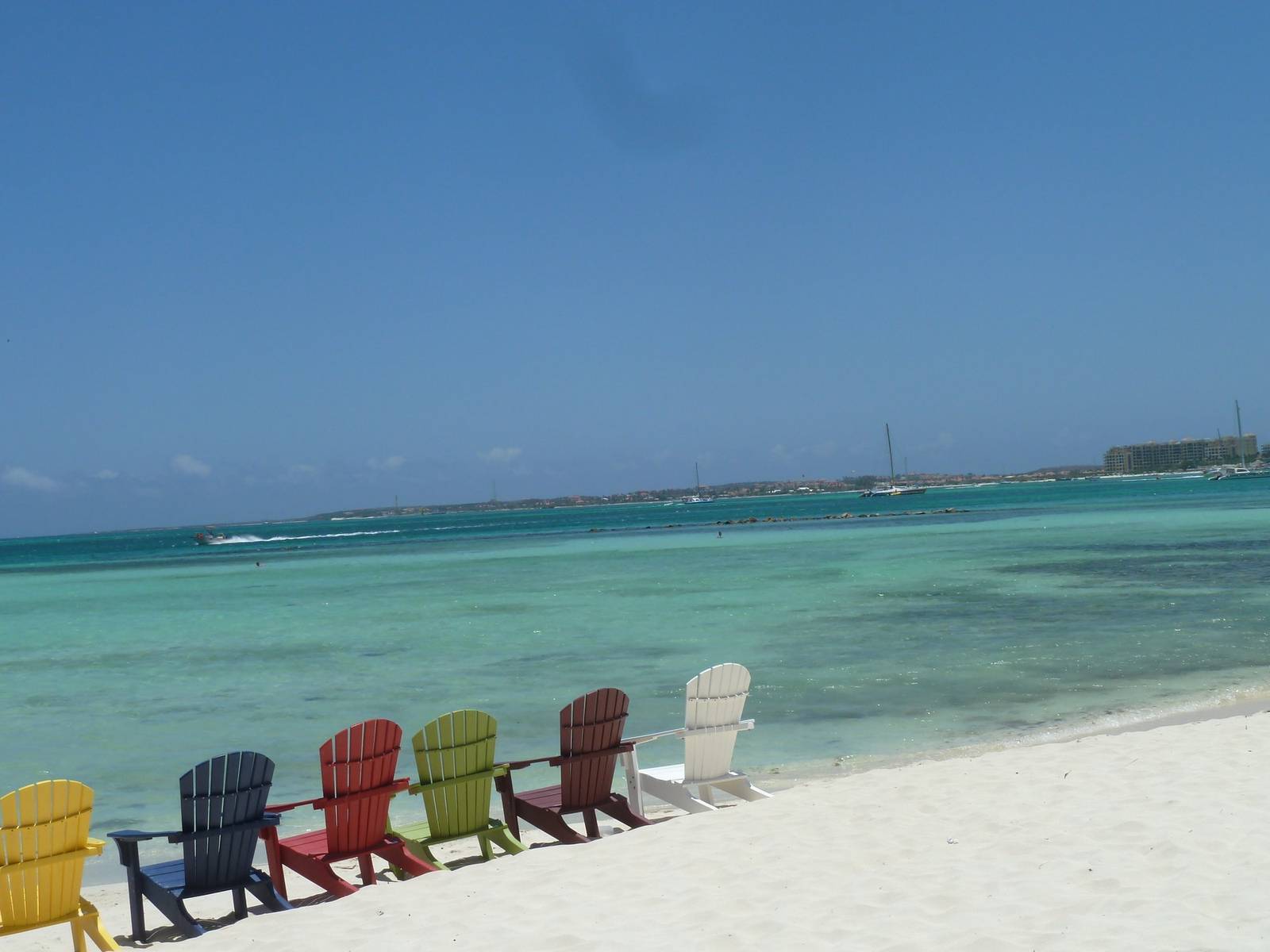 Colourful beach chairs on white sand and turquoise water in Aruba