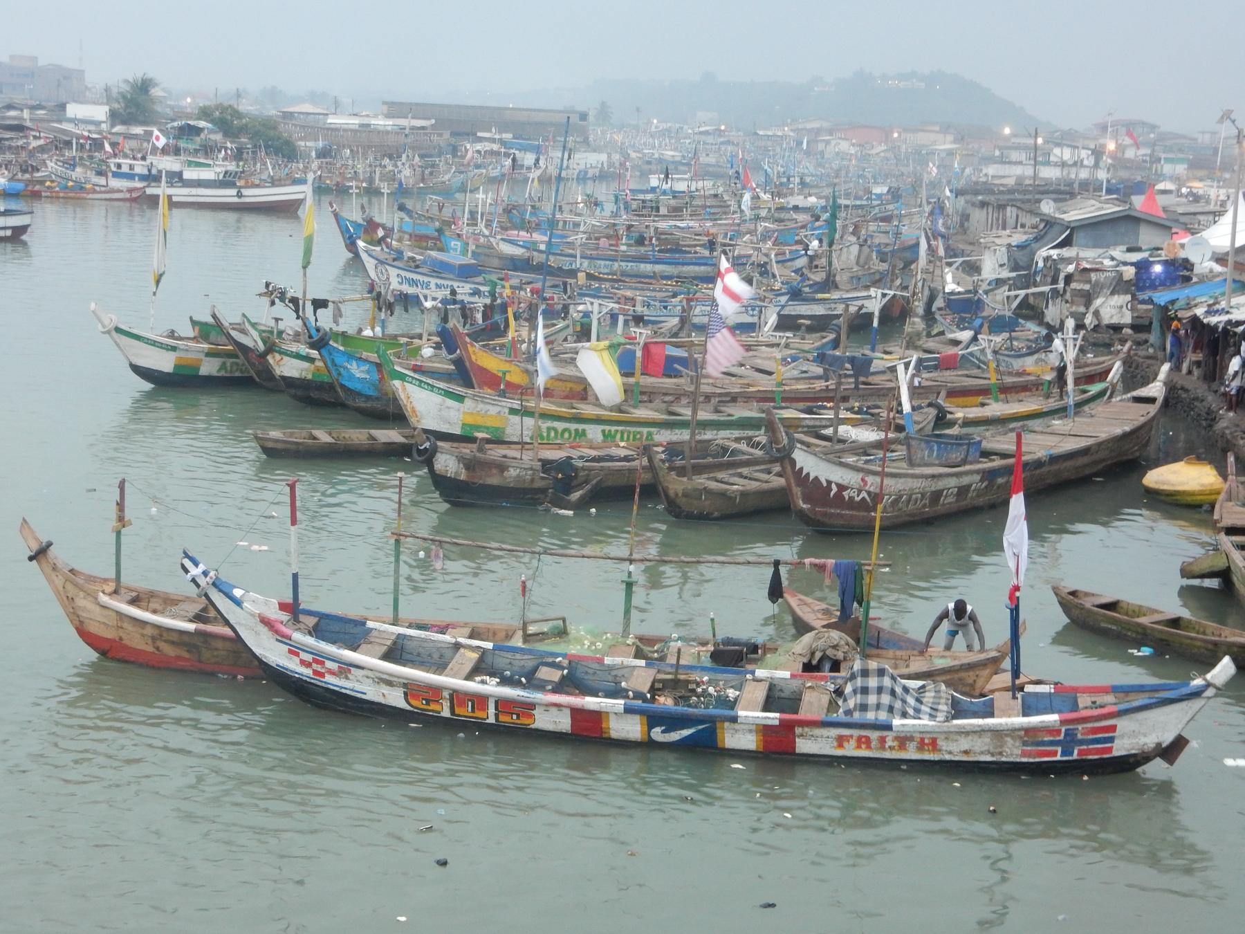 Painted fishing boats crowding a harbour on the coast of Ghana